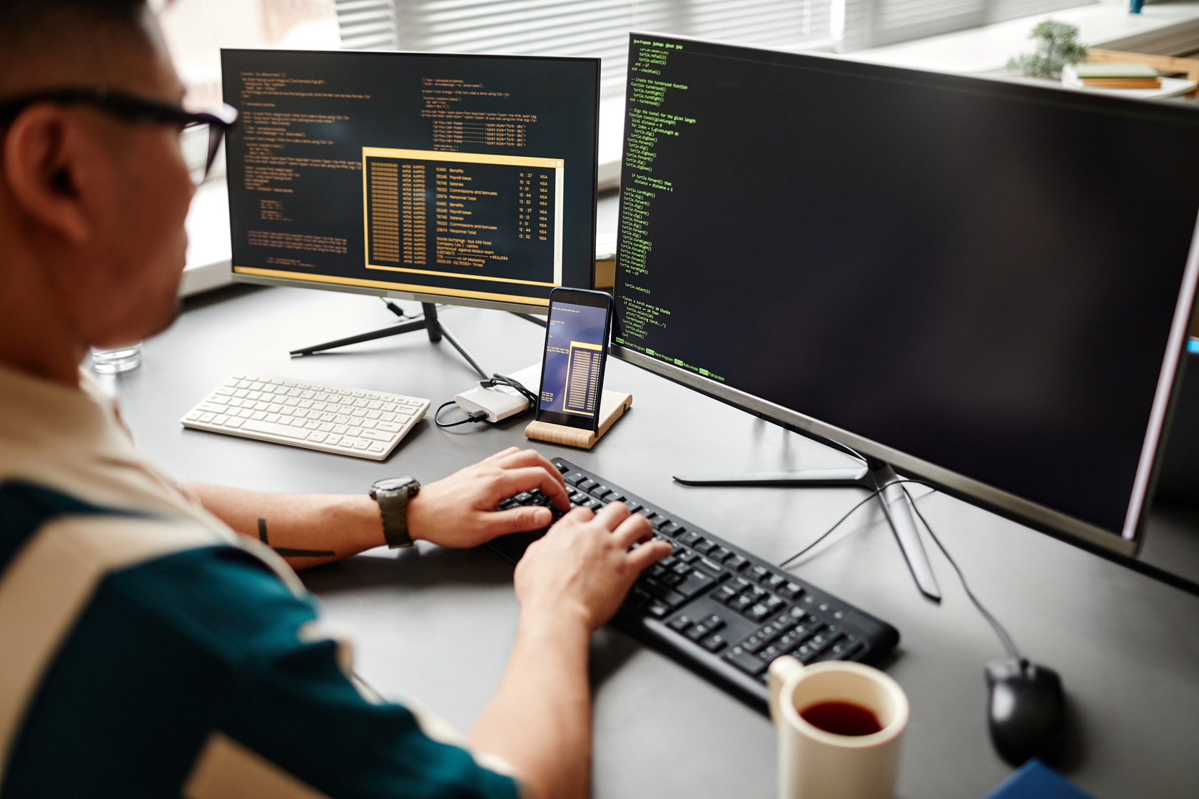 Programador trabajando con código en pantallas dobles.